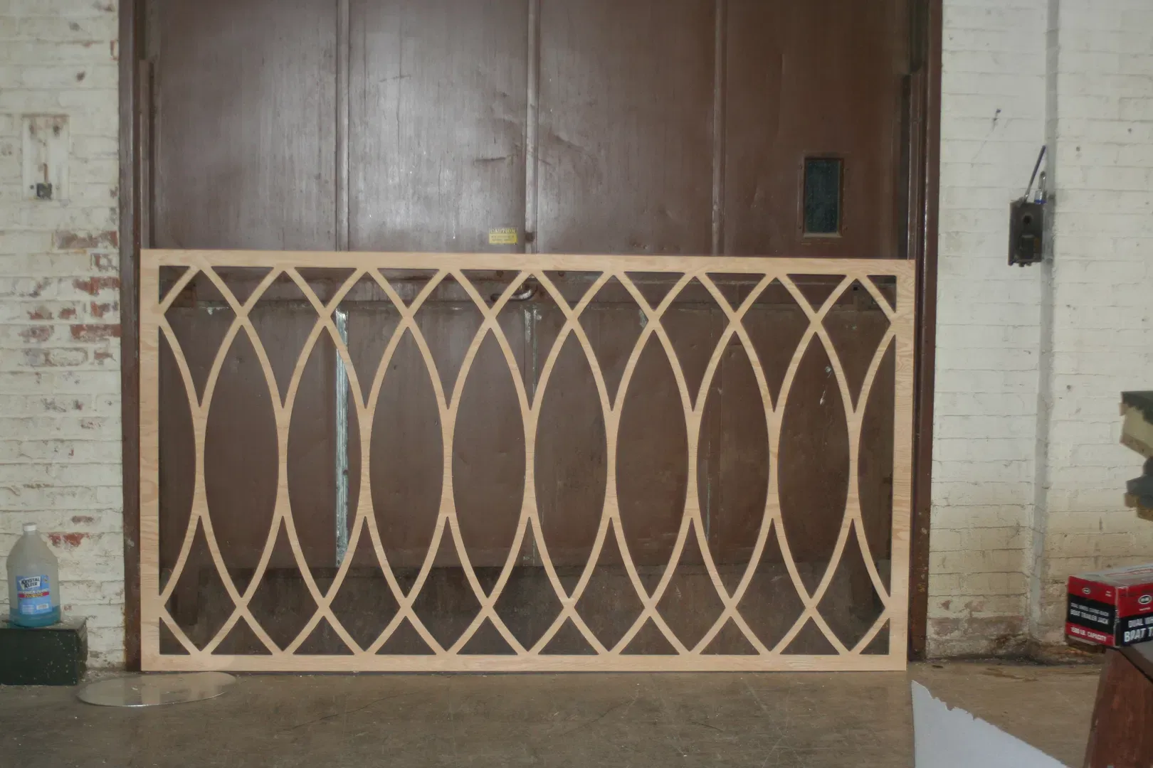 A custom-fabricated wooden lattice screen featuring a repeating Gothic arch, or "vesica piscis," geometric pattern. Crafted in our workshop, this CNC-cut panel showcases clean lines and precise joinery, intended for use as a decorative room divider, architectural wall feature, or cabinet insert. The raw birch plywood finish highlights the quality of the laser or router work, demonstrating our capacity to produce intricate, large-scale wood designs for custom interior projects.