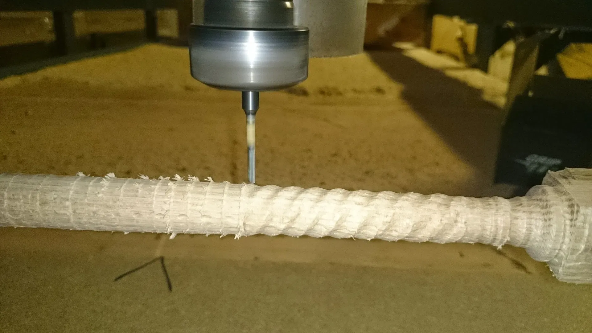 A close-up view of our CNC router in action, carving precise, decorative fluting into a wooden spindle. The machine is mid-process, demonstrating the accuracy and efficiency of our custom woodworking capabilities. This highlights the blend of traditional craftsmanship and modern technology we use to create detailed furniture components and architectural woodwork.